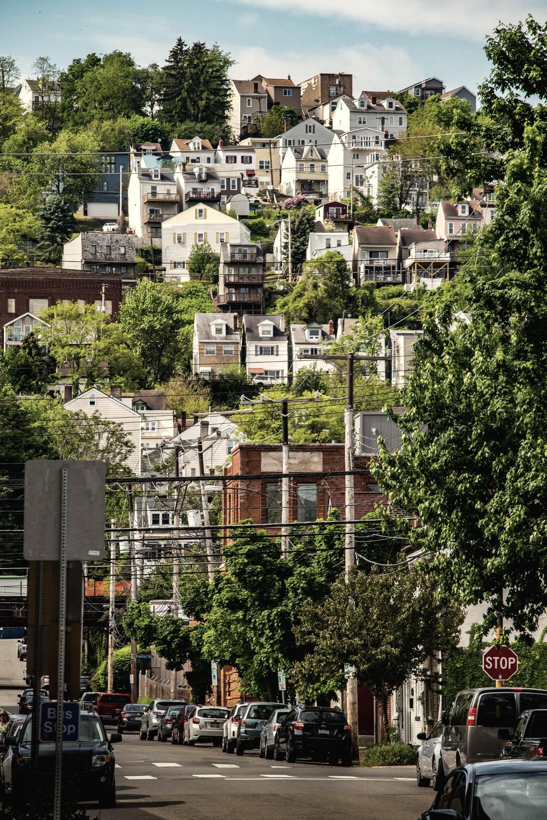 Houses stacked up a Pittsburgh hillside above a commercial street